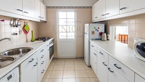 A modern kitchen with white cabinets, a stainless steel sink, and a microwave. - Best location in Lagos with superb pool area! (Lagos)