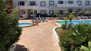 A resort with a swimming pool, lounge chairs, and a building with blue trim. - Best location in Lagos with superb pool area! (Lagos)