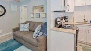 Ein Wohnzimmer mit einer Couch, einem Deckenventilator und einer Wanduhr.