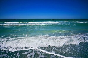 A beach with waves crashing onto the shore under a clear blue sky. - 3BR Peaceful Pond Paradise near Clearwater, Highland Rec w/ Free Parking & Wi-Fi (Largo)