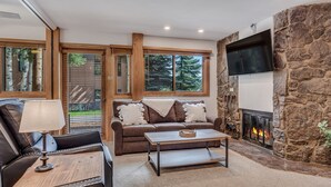 A cozy living room with a stone fireplace, a leather sofa, and a coffee table. - 🏔️Ski Access~Hot Tub~Studio Premier 102🏔️ (Snowmass Village)