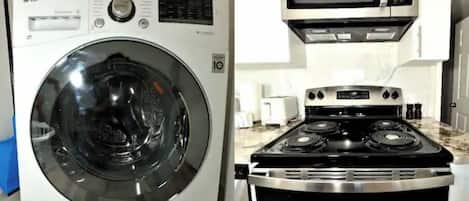 A compact kitchen with a microwave, stove, and washing machine.