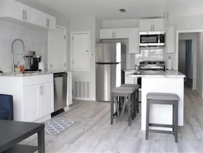 Enjoy cooking in this well-lit kitchen with a refrigerator, microwave, and oven, plus a convenient island with bar stools.