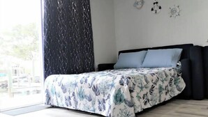 Un dormitorio con cama, ventana con cortina y dos lámparas de pared.