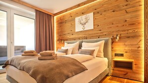 Un dormitorio moderno con un panel de pared de madera, una cama grande con muchas almohadas y vistas al exterior.