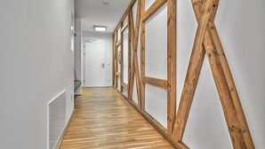 Un pasillo con vigas de madera, una puerta blanca al final y suelo de madera.