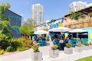 Enjoy al fresco dining in a lush, urban oasis with tables, chairs, and umbrellas.