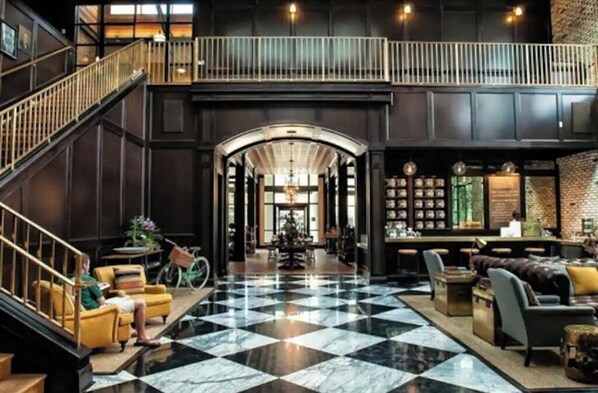 Step into our elegantly designed lobby with a soaring ceiling and mezzanine level, featuring comfortable seating areas and a staircase.