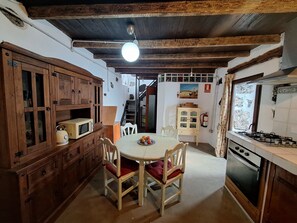 A kitchen with wooden cabinets, a dining table with chairs, a microwave, and a gas stove.