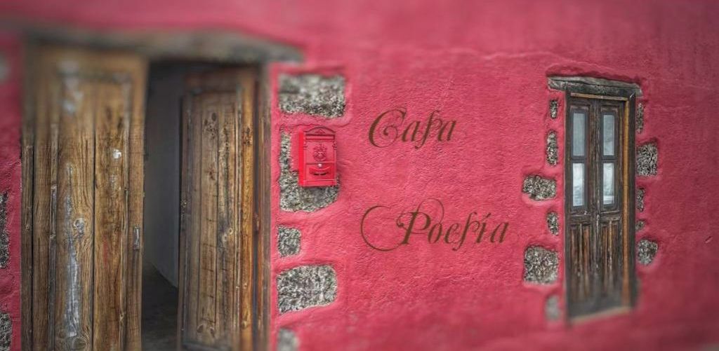 A rustic building facade with wooden doors and a red mailbox.
