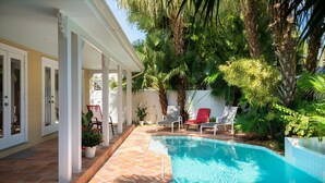 A swimming pool with a tiled deck, surrounded by palm trees and potted plants. - Tranquil Beauty-Private Pool - Outside Lanai-Beaches Nearby (Key West)