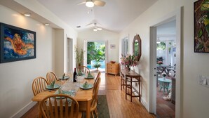 A dining area with a wooden table set for four, a ceiling fan, and a view of the outdoor patio. - Tranquil Beauty-Private Pool - Outside Lanai-Beaches Nearby (Key West)