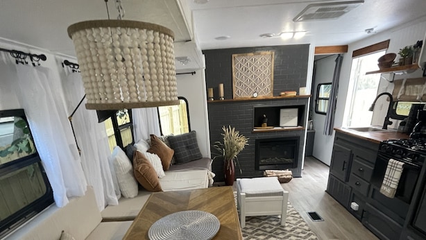 A modern RV interior with a wooden dining table, sofa, and kitchenette. - Delightful and cozy RV with outdoor space (St. Petersburg)