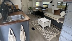 A compact RV kitchen with a sink, stove, and a small dining area. - Delightful and cozy RV with outdoor space (St. Petersburg)