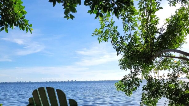 Una silla Adirondack verde junto a un lago.