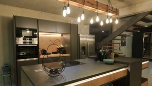 Una cocina moderna con electrodomésticos de acero inoxidable, una isla de madera e iluminación colgante.