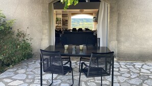 A stone patio with a table and chairs, an arched doorway leading to a seating area with a view of the countryside. - Villa provençale 6 pers, Piscine à débordement/Vue exceptionnelle/2 SDB, Ventoux (Villedieu)