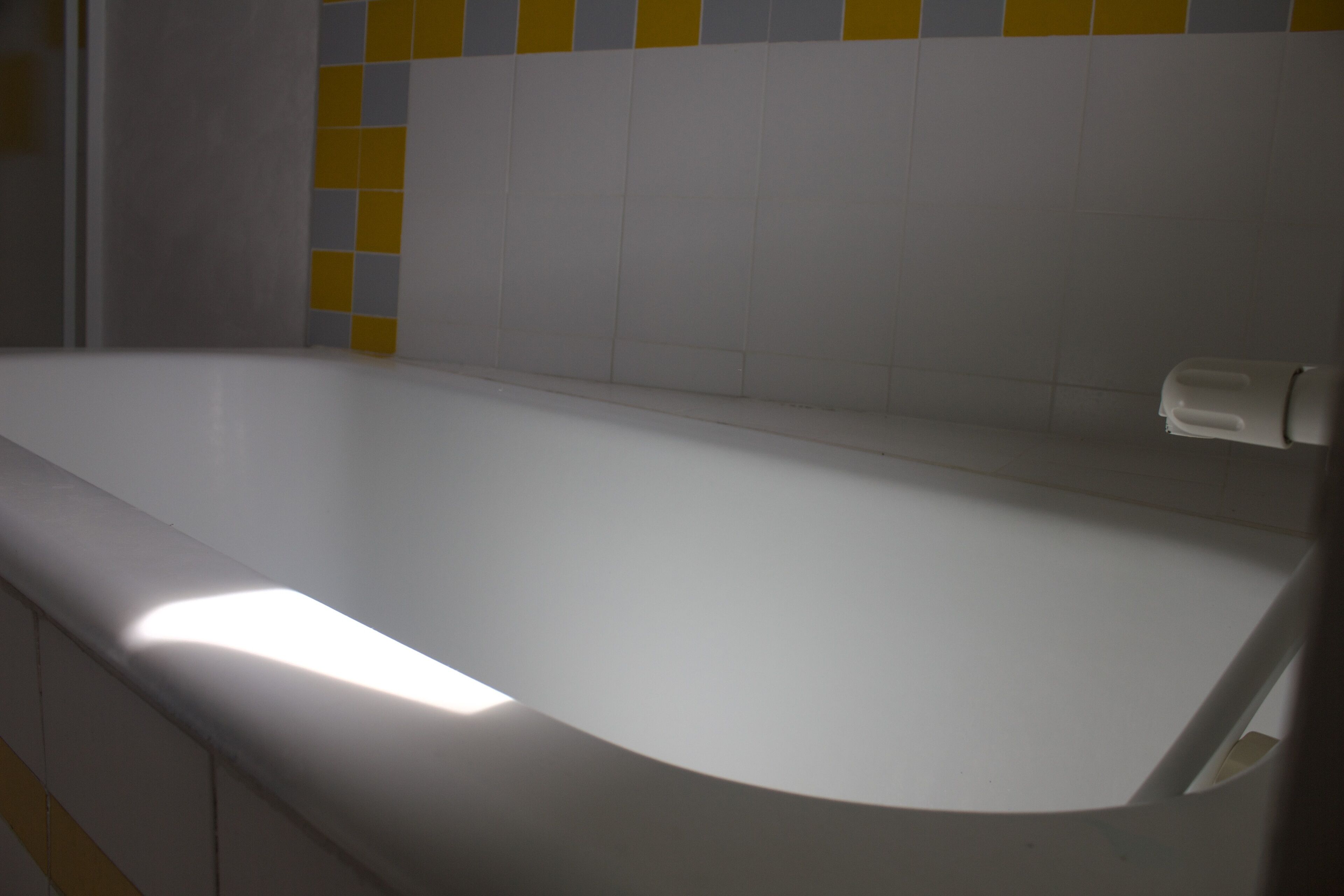 A white bathtub with a towel dispenser on the right side.
