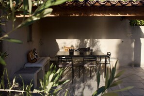Une terrasse avec une table et des chaises, un banc et une guitare.