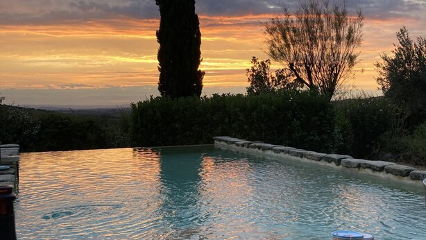 A poolside dining area with a sunset view, surrounded by greenery and a tall tree. - Villa provençale 6 pers, Piscine à débordement/Vue exceptionnelle/2 SDB, Ventoux (Villedieu)