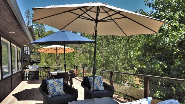 A deck with outdoor furniture, including sofas and a table, and two umbrellas providing shade. - Tree View - Murphys Vacation Rentals (Murphys)