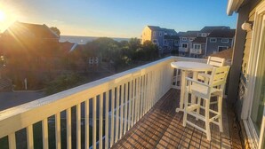 A balcony with a white railing, a small table, and chairs.