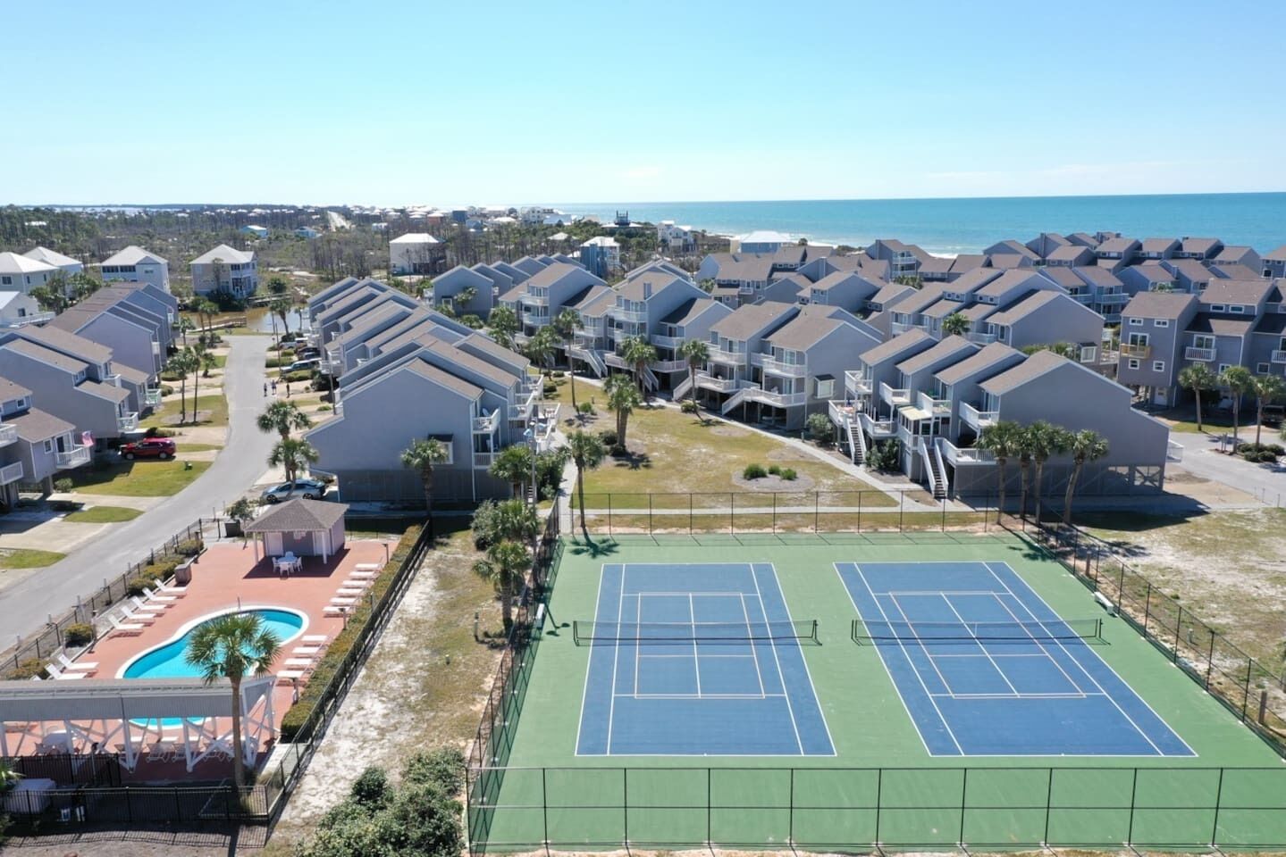 A residential area with multiple two-story houses, a tennis court, and a swimming pool.