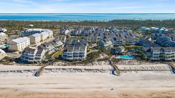 Ein Küstenwohngebiet mit Häusern direkt am Strand, einer Promenade und freiem Blick auf das Meer.