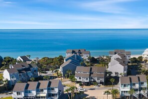 A coastal residential area with multi-story buildings, a clear view of the ocean, and a paved road.