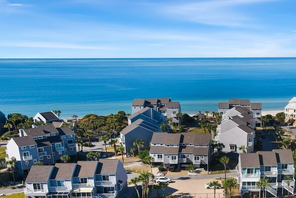 A coastal residential area with multi-story buildings, a clear view of the ocean, and a paved road.