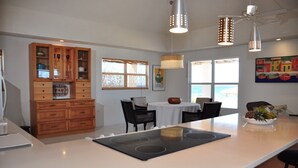 A modern kitchen with a central island, wooden cabinets, and a dining area with a table and chairs.