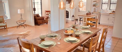 A spacious dining area with a wooden table set for six, surrounded by wooden chairs.