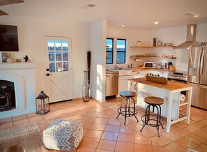 Eine moderne Küche mit einer zentralen Kochinsel, Barhocker, einem eingebauten Backofen und einer Mikrowelle.