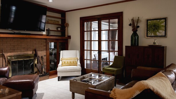 A living room with a fireplace, leather furniture, a television, and a large window.