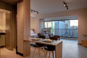 Um apartamento moderno com área de refeições, sofá e varanda com vista para a cidade.