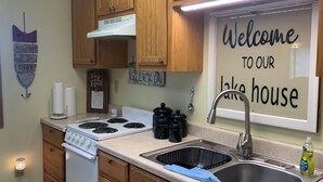 Una cocina con armarios de madera, una estufa blanca, un fregadero y un cartel de bienvenida.