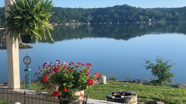 Una vista tranquila del lago con un balcón, una planta en maceta y una chimenea.