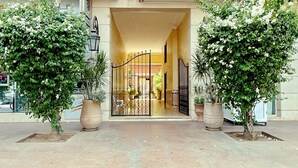 A hotel entrance with a gated driveway, potted plants, and a visible interior through the gate. - Modern 140 m² duplex - 2 bedrooms with terrace and shared swimming pool. Gueliz. (Marrakech)