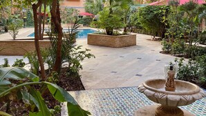 A courtyard with a swimming pool, surrounded by various plants and a fountain. - Modern 140 m² duplex - 2 bedrooms with terrace and shared swimming pool. Gueliz. (Marrakech)
