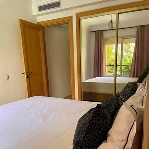 Una habitación de hotel con cama, armario y ventana con cortinas.