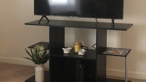 Ein Flachbildfernseher auf einem schwarzen Ständer, darunter ein kleiner Tisch.