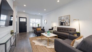 A modern living room with a sofa, coffee table, and a TV mounted on the wall.