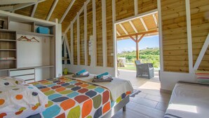 Ein Schlafzimmer mit Bett, Kleiderschrank, Schreibtisch und einem Fenster mit Blick ins Freie.