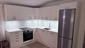 A modern kitchen with white cabinets, a stainless steel refrigerator, a built-in oven, and a sink. - Wonderful house with new kitchen in beautiful nature and close to activities (Skåne län)
