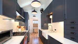 Una cocina moderna con armarios oscuros, una encimera blanca, un horno empotrado y un lavabo.