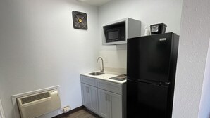 A compact kitchen with a microwave, refrigerator, and sink. - Motel 6 Artesia, NM  (Artesia)