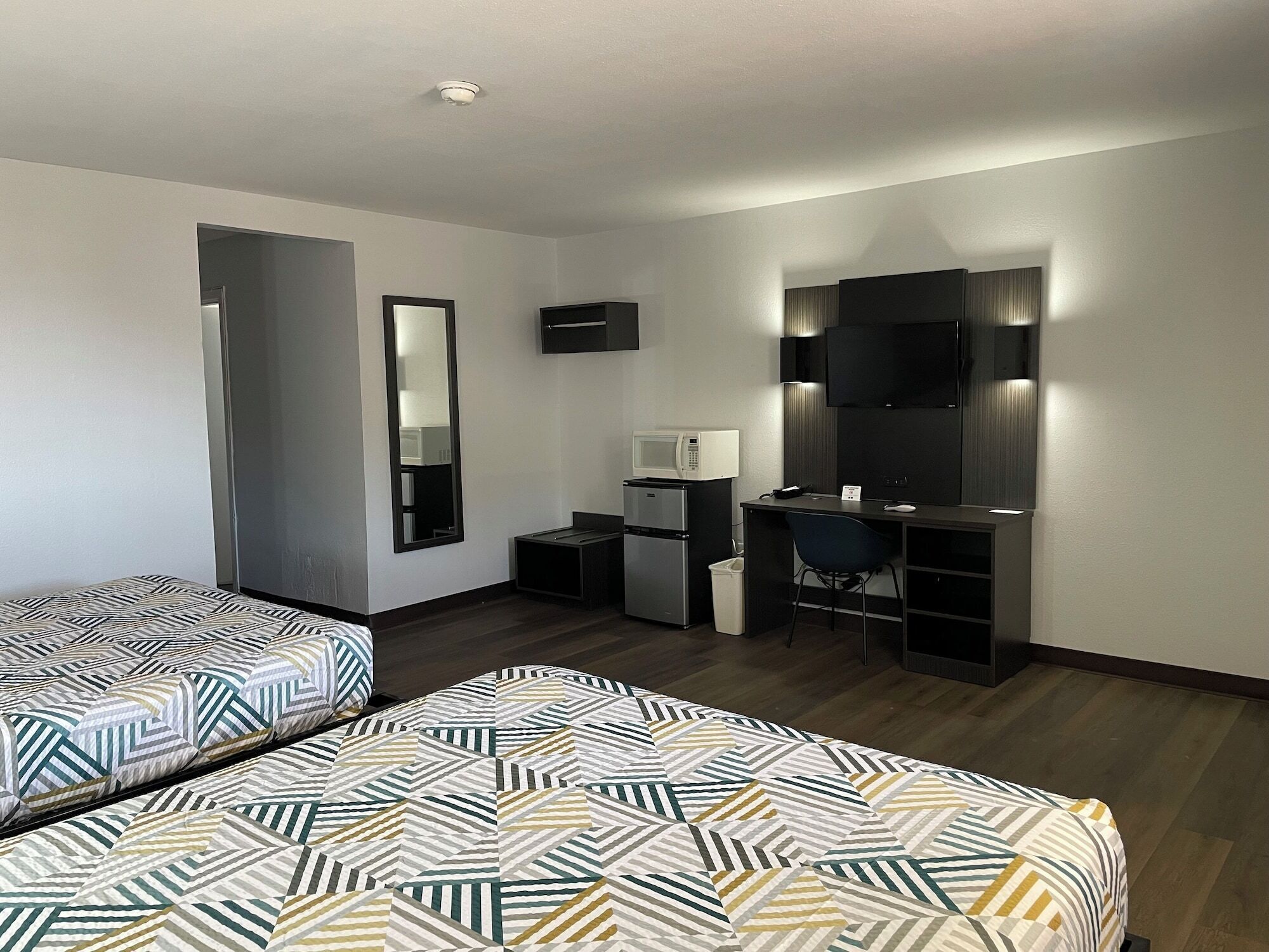 Habitación de hotel con dos camas, un escritorio, microondas, basurero y televisor.