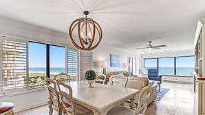 Une salle à manger spacieuse avec vue sur l’océan, un lustre et un ventilateur de plafond.