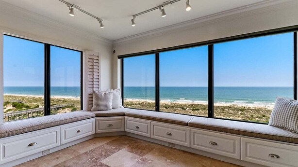 Un coin salon avec de grandes fenêtres donnant sur une plage.