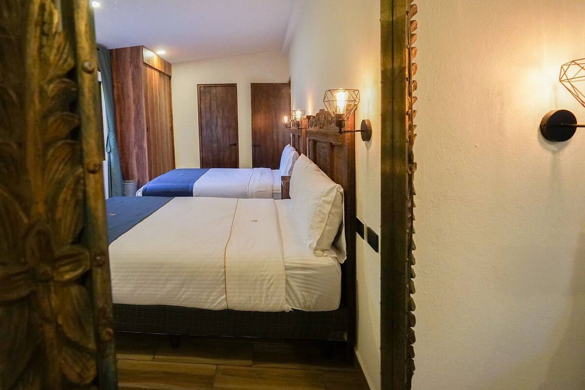 A hotel room with two beds, wooden walls, and a decorative mirror.